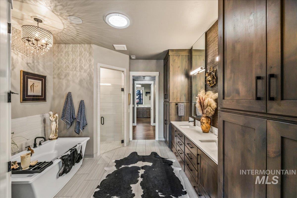 Full bathroom with a bathtub, double vanity, and a stall shower