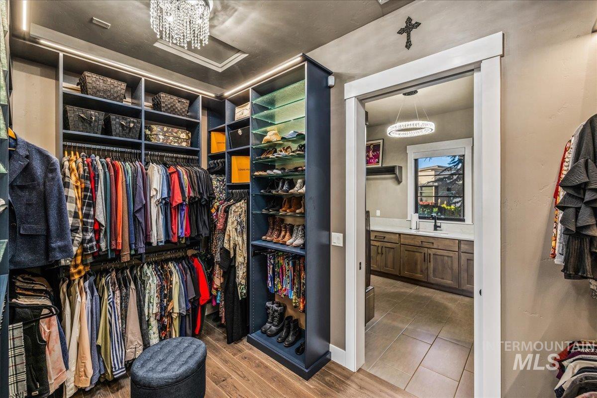 Walk in closet with a chandelier and wood finished floors