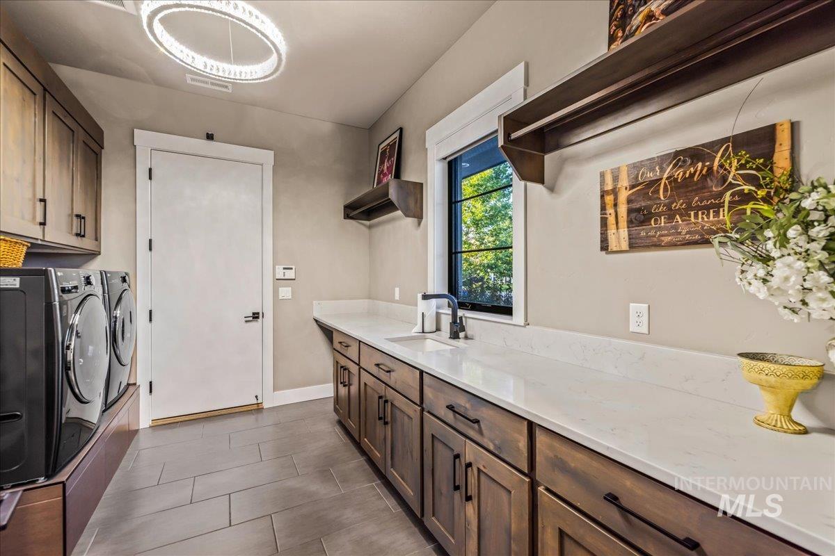 Washroom featuring washer and clothes dryer, cabinet space, and dark tile patterned floors