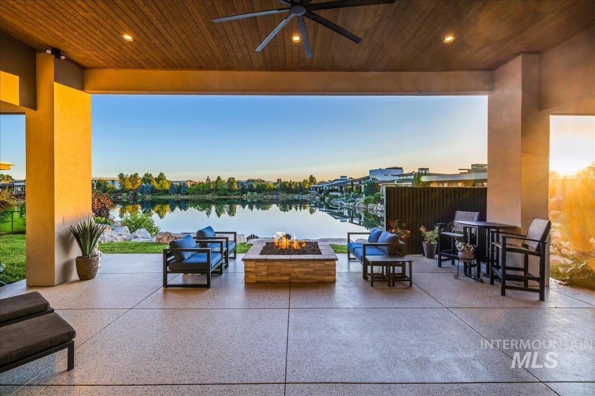 View of patio with a fire pit, a ceiling fan, and a water view