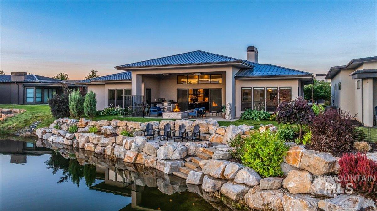 Back of house with a metal roof, a standing seam roof, a chimney, a patio area, and stucco siding