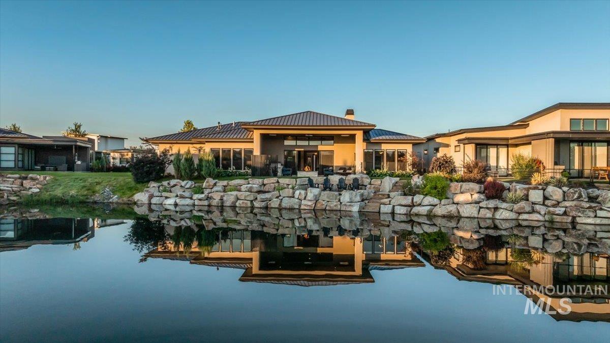 Rear view of house with a chimney, stucco siding, and a metal roof
