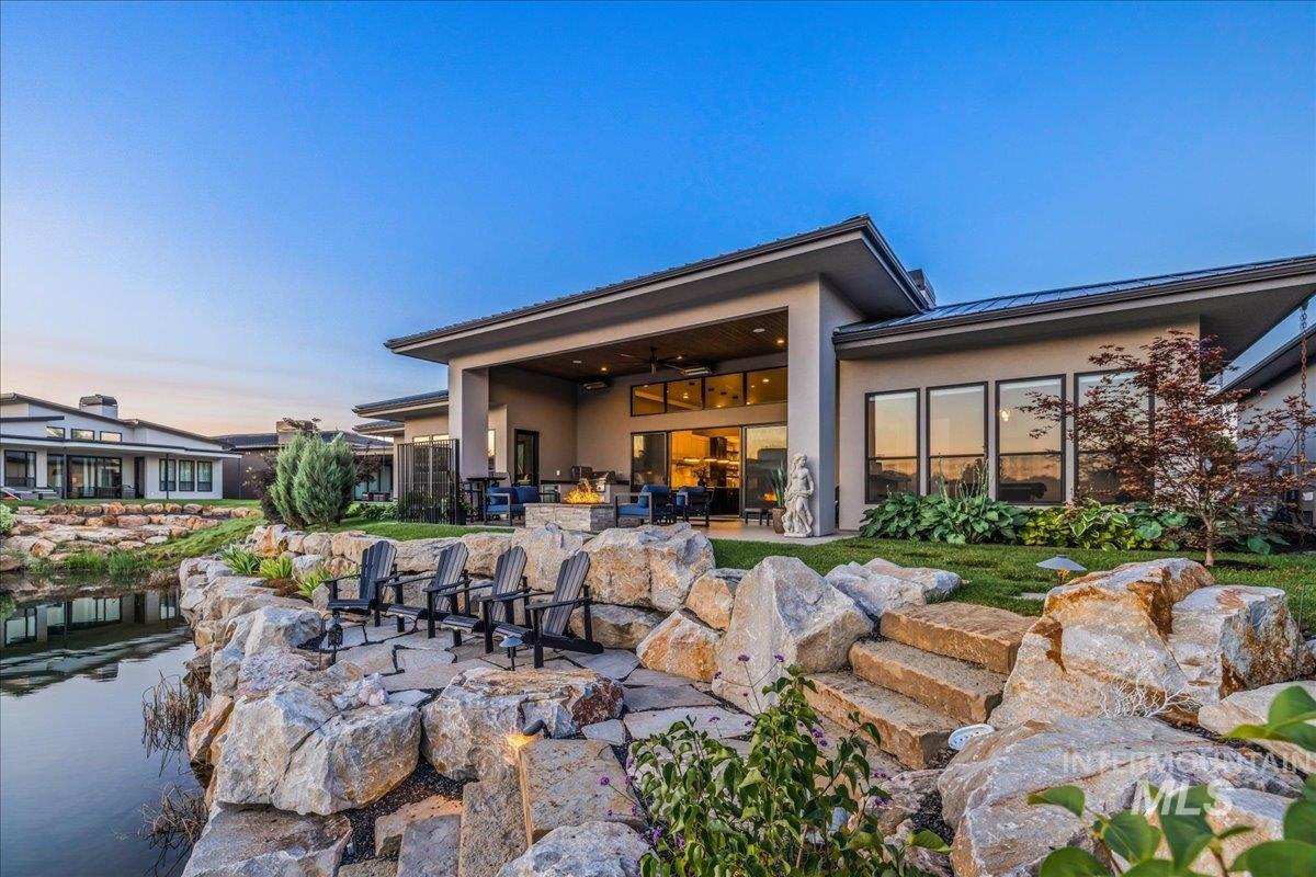 Back of property at dusk with a standing seam roof, a metal roof, a ceiling fan, a patio area, and stucco siding