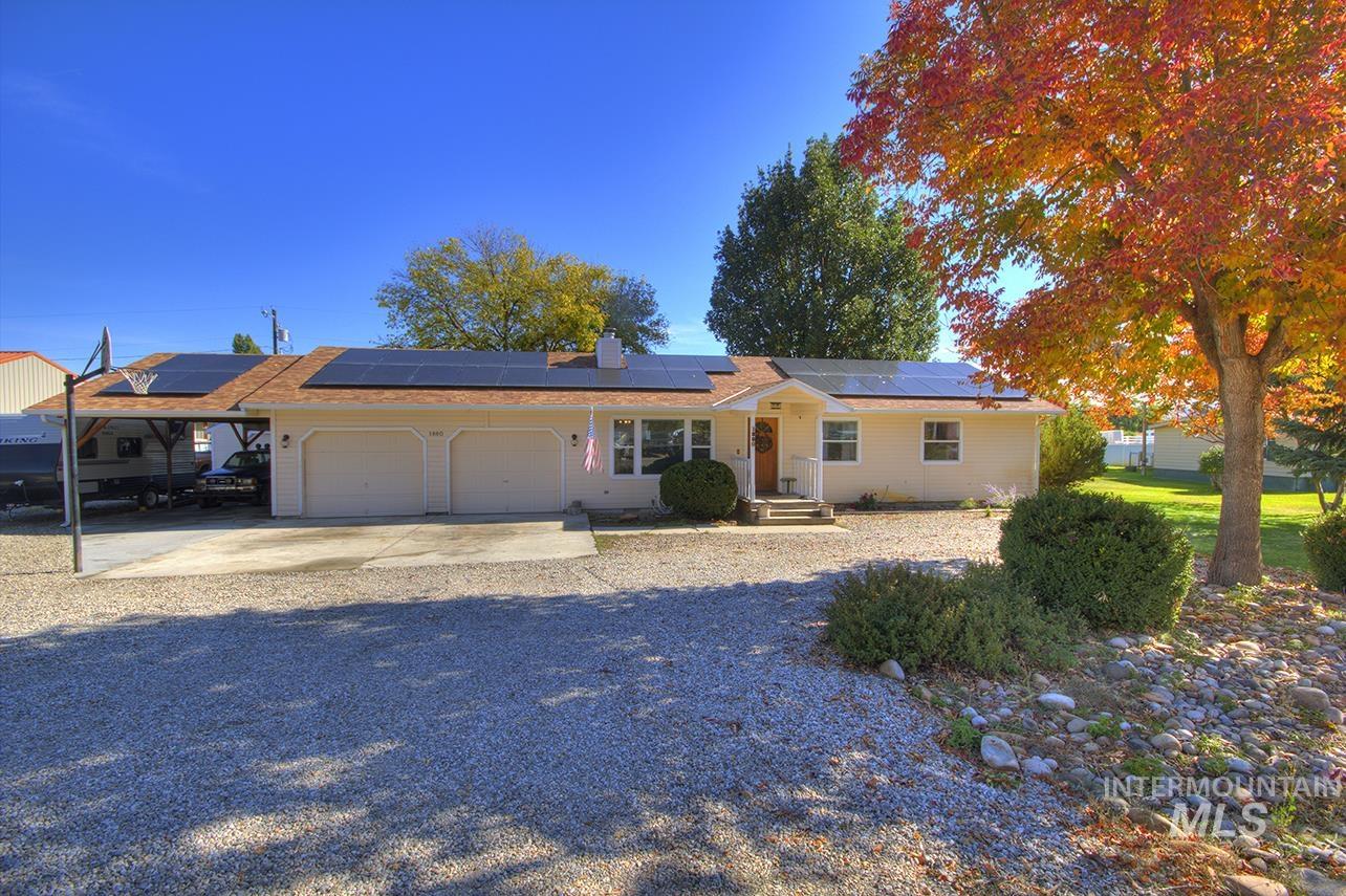 Ranch-style house with a garage, driveway, a chimney, and roof mounted solar panels