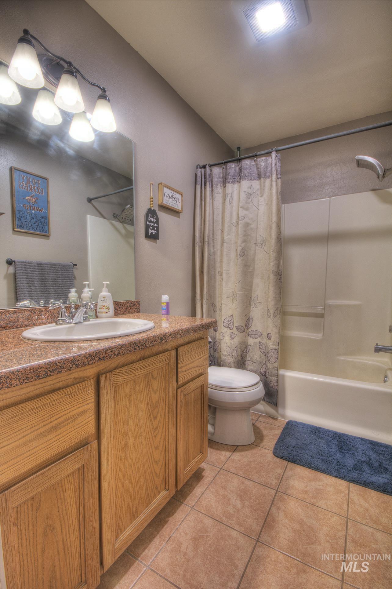 Bathroom featuring vanity, shower / bathtub combination with curtain, and light tile patterned floors