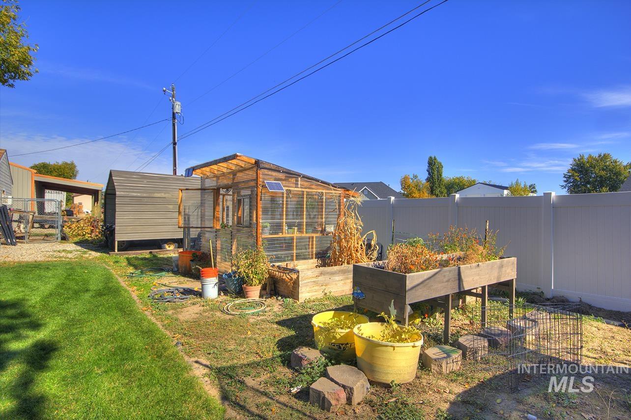 Fenced backyard featuring an outdoor structure, a vegetable garden, and an exterior structure