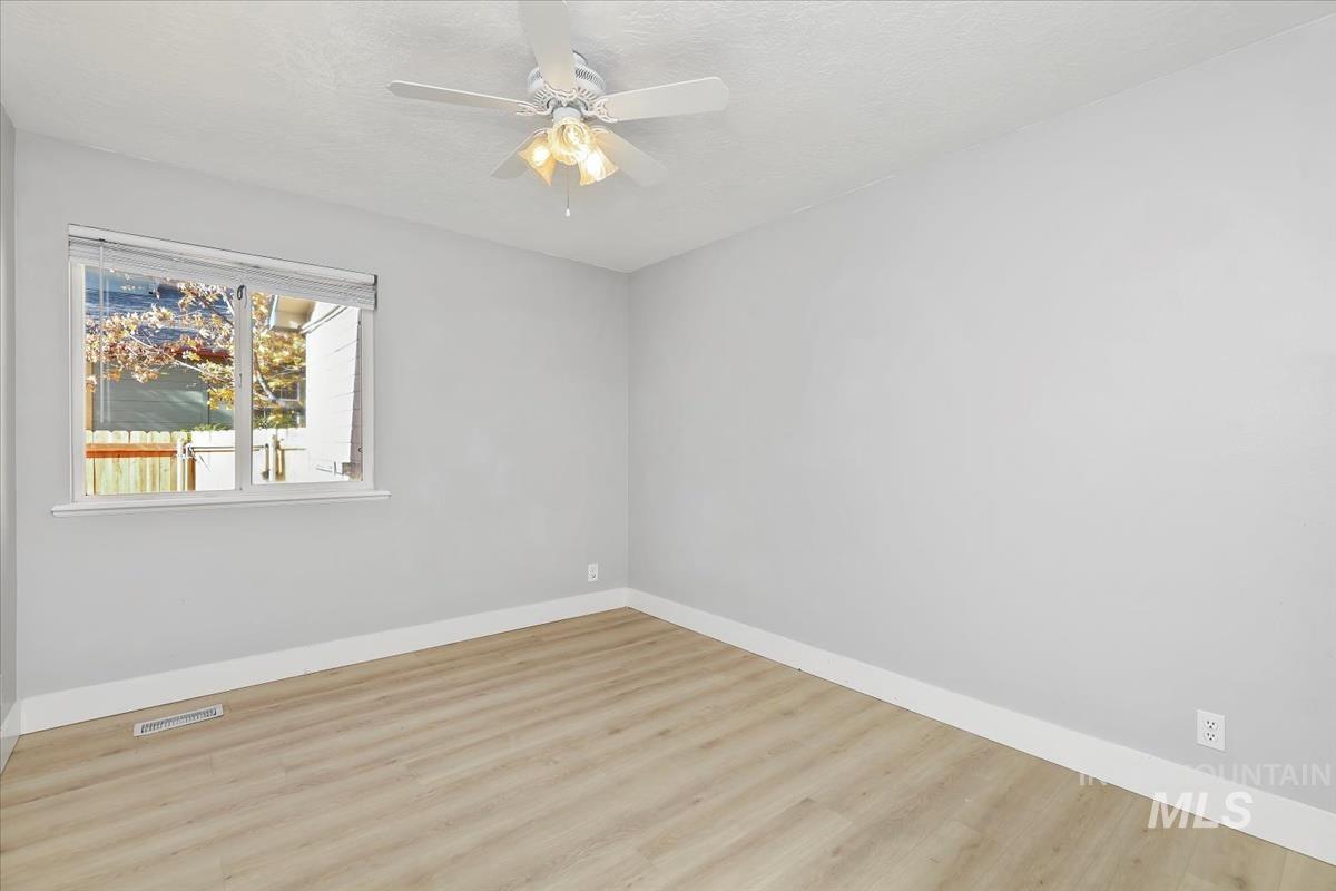 Empty room with wood finished floors, a ceiling fan, and a textured ceiling