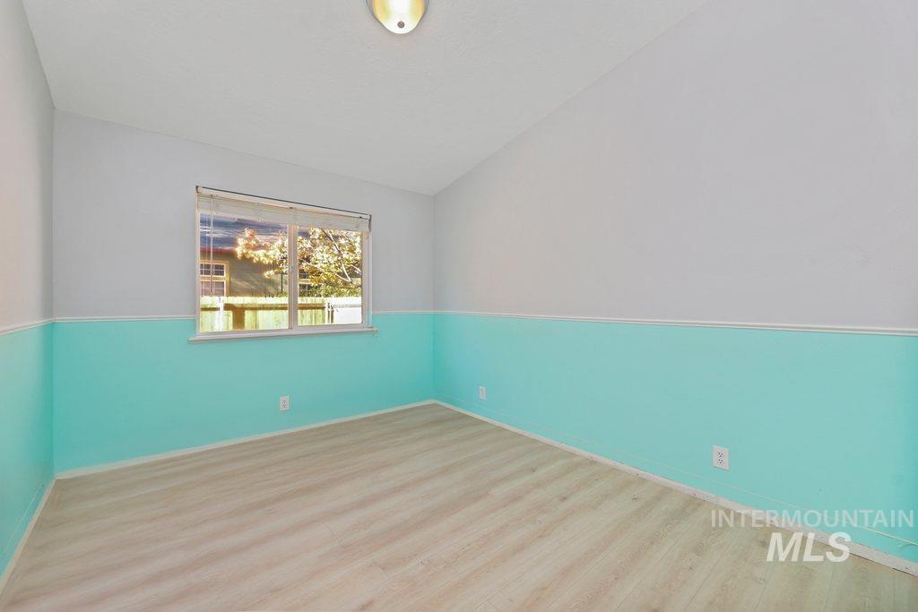 Unfurnished room featuring wood finished floors and lofted ceiling