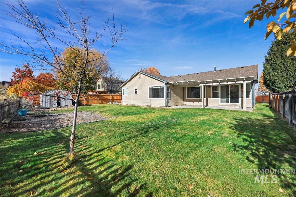 Rear view of property featuring a patio area, a fenced backyard, and a storage unit