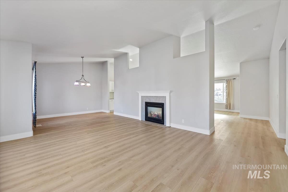 Unfurnished living room with light wood-style flooring, a high end fireplace, and a chandelier
