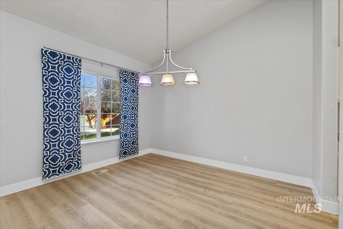 Unfurnished dining area with lofted ceiling, wood finished floors, and a chandelier