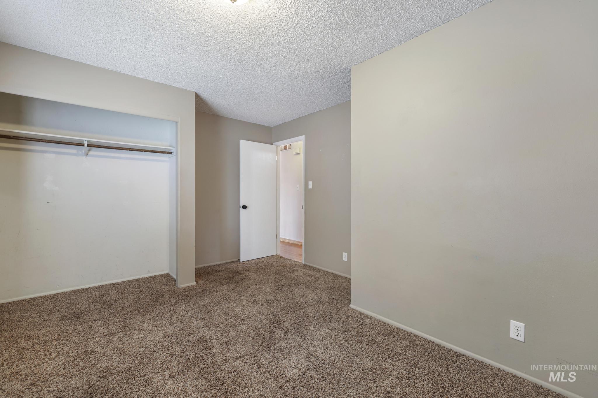 Unfurnished bedroom with a textured ceiling, carpet, and a closet