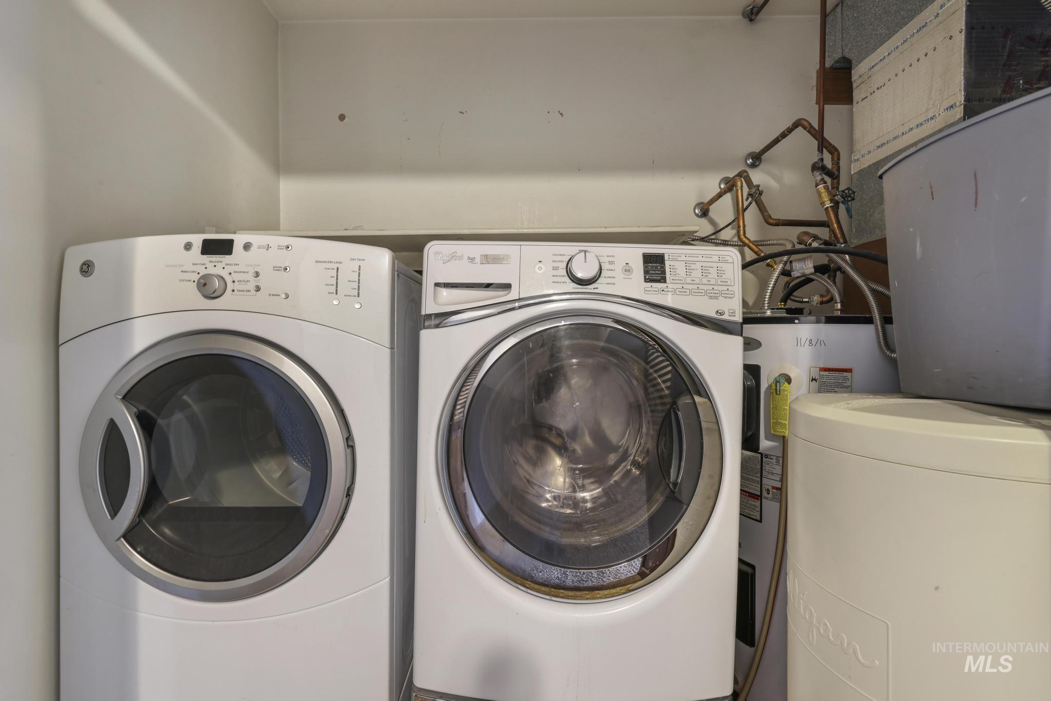Washroom featuring water heater and washer and clothes dryer