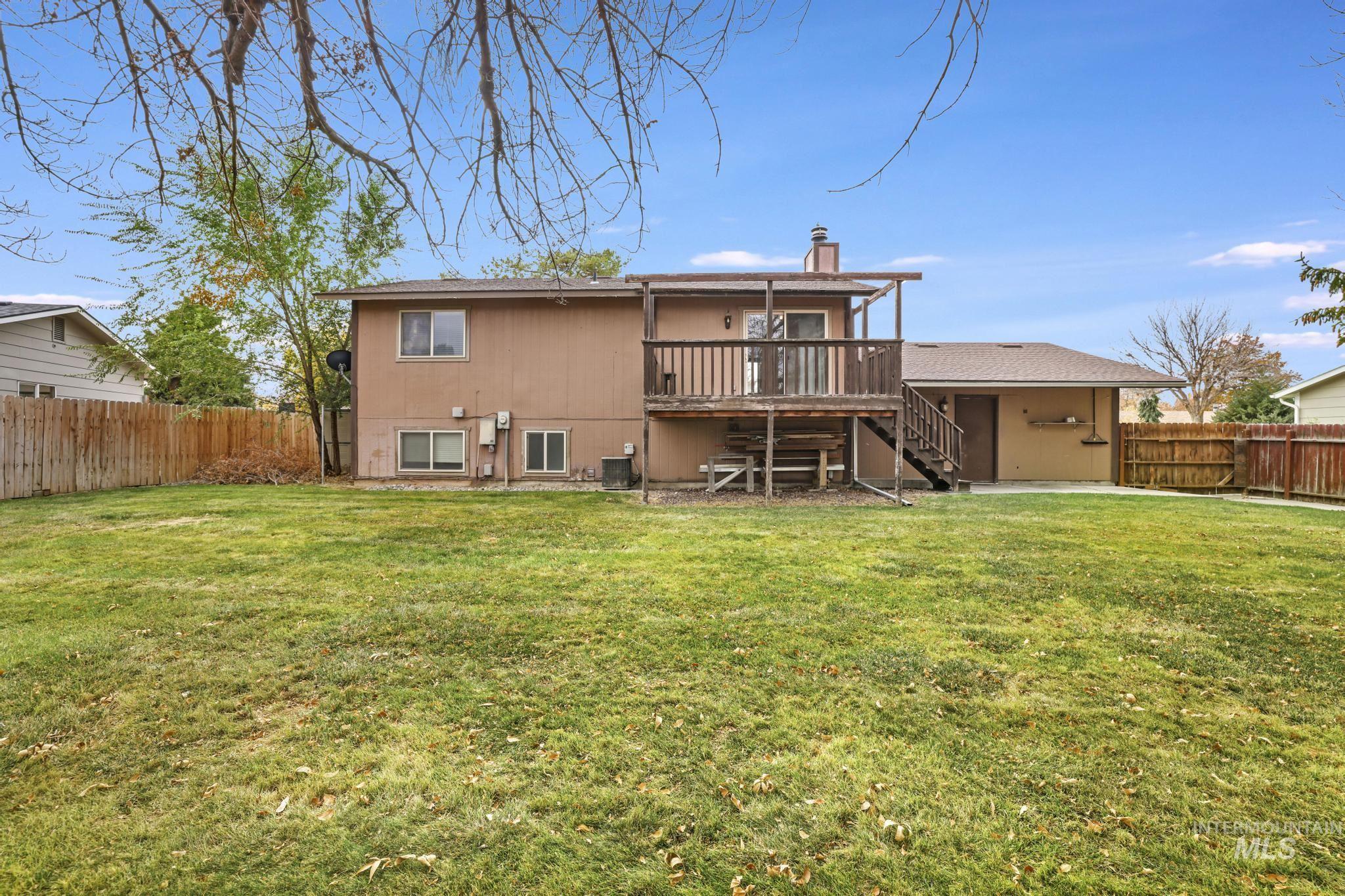Rear view of property featuring stairs, a fenced backyard, a deck, and a chimney
