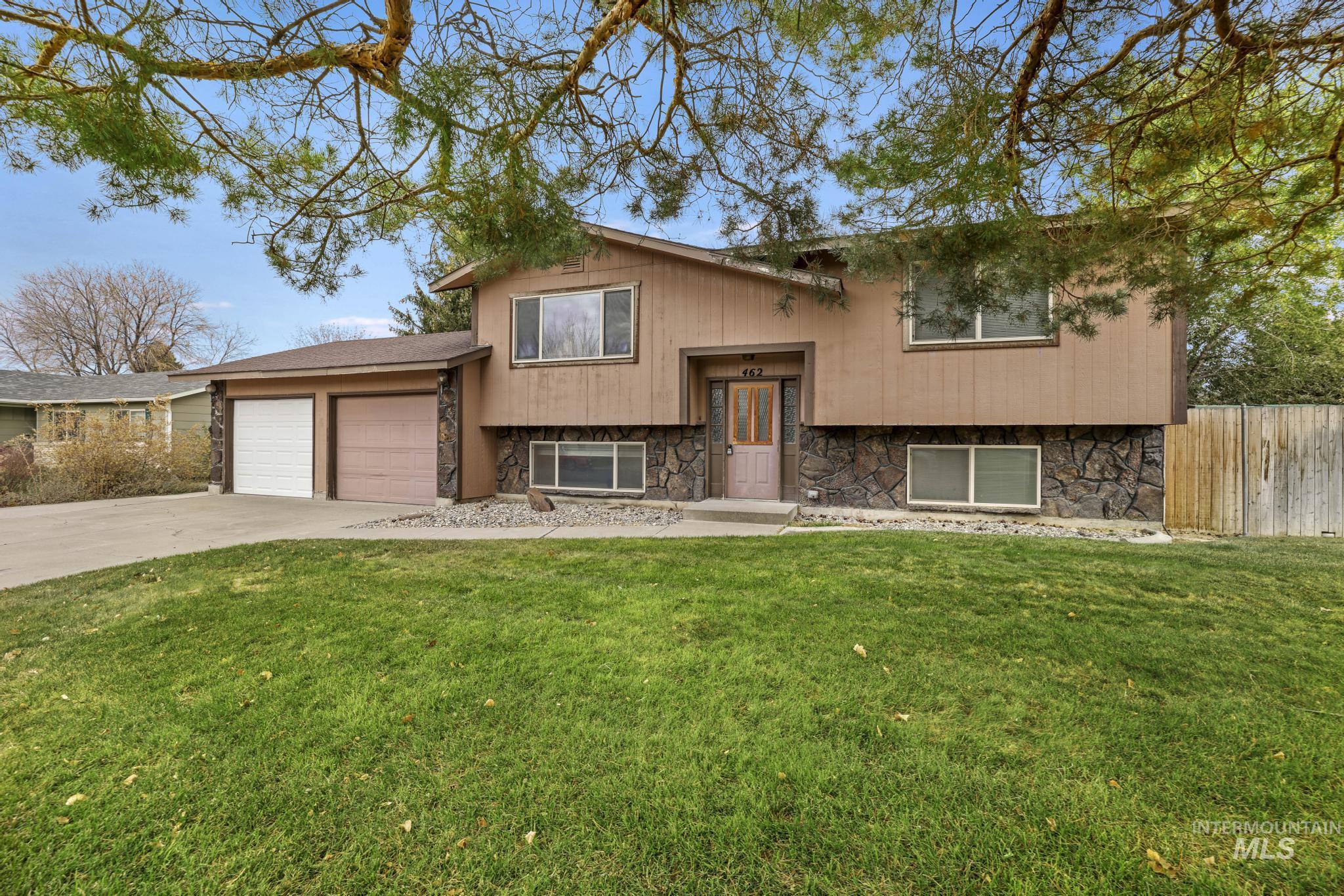 Bi-level home featuring stone siding, concrete driveway, and an attached garage