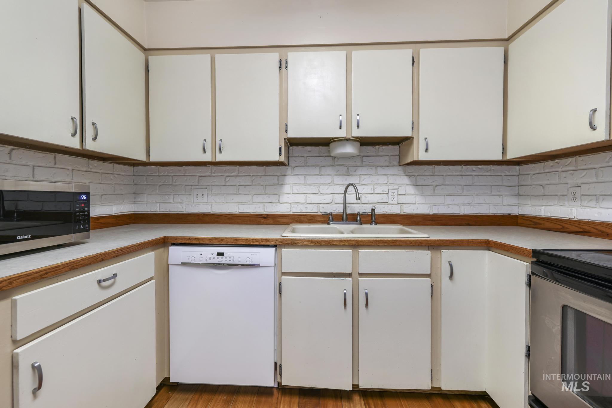 Kitchen with white cabinetry, appliances with stainless steel finishes, light countertops, and tasteful backsplash