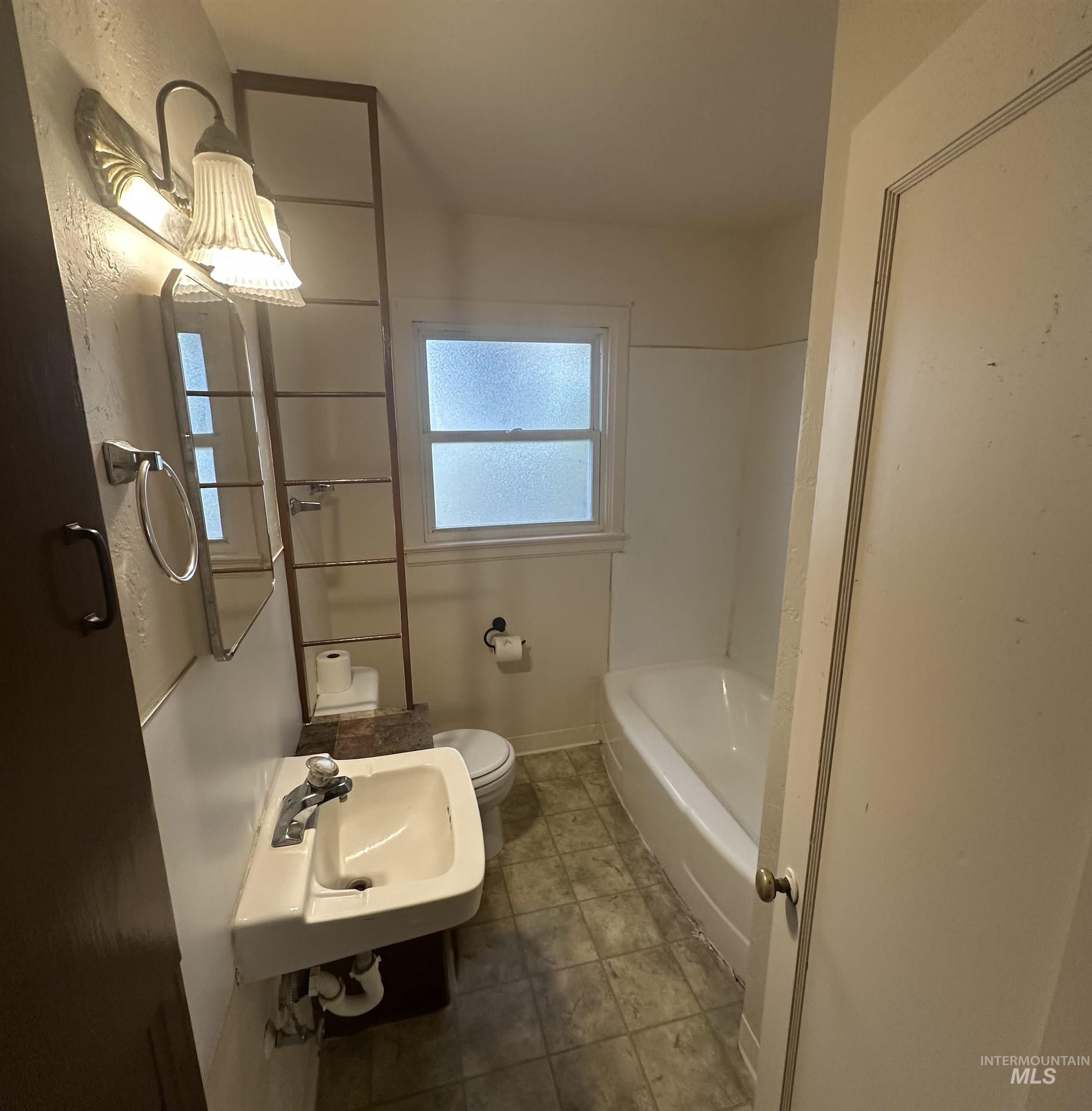 Full bath featuring a bathtub and dark tile patterned flooring