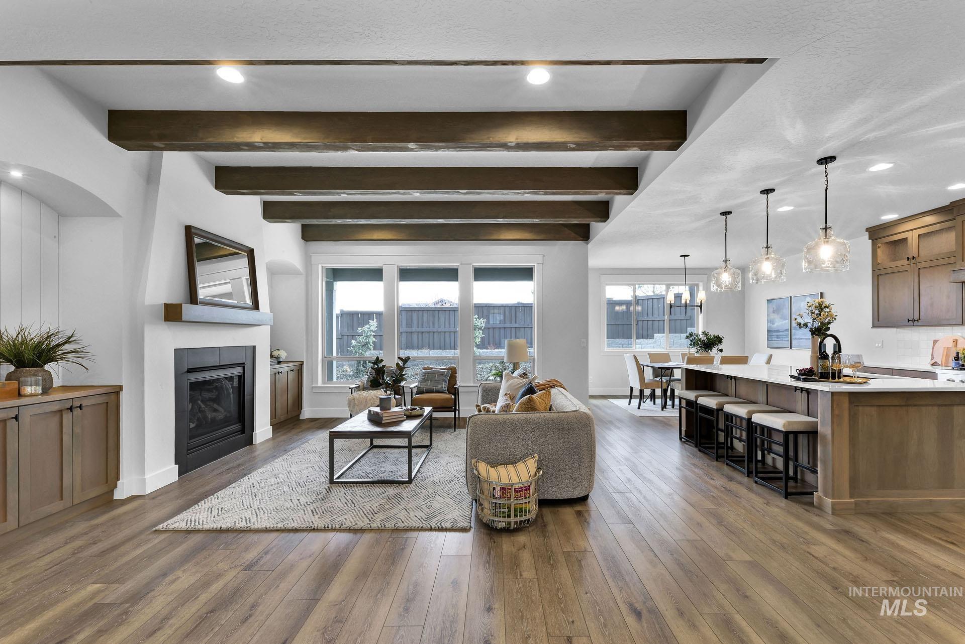 Living room with recessed lighting, beam ceiling, healthy amount of natural light, dark wood finished floors, and a glass covered fireplace