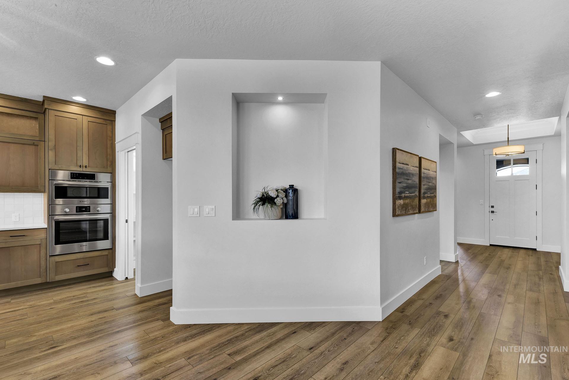 Kitchen featuring recessed lighting, brown cabinets, light wood-style floors, a textured ceiling, and decorative backsplash