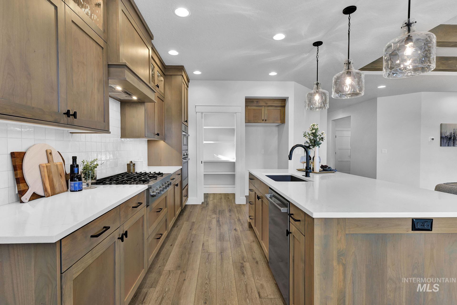 Kitchen with a spacious island, brown cabinetry, recessed lighting, light stone countertops, and light wood-style flooring