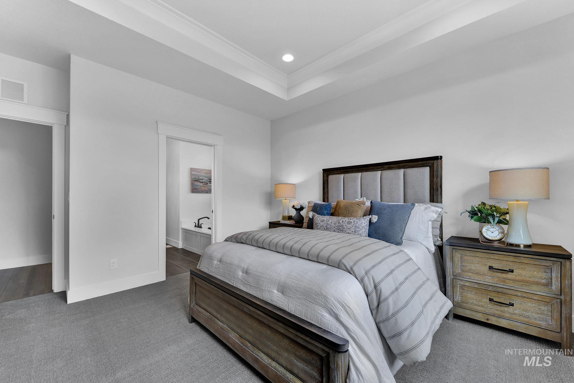 Bedroom with a tray ceiling, carpet flooring, ensuite bathroom, crown molding, and recessed lighting