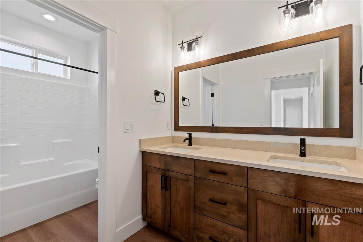 Full bathroom featuring double vanity, dark wood-style flooring, and bathtub / shower combination