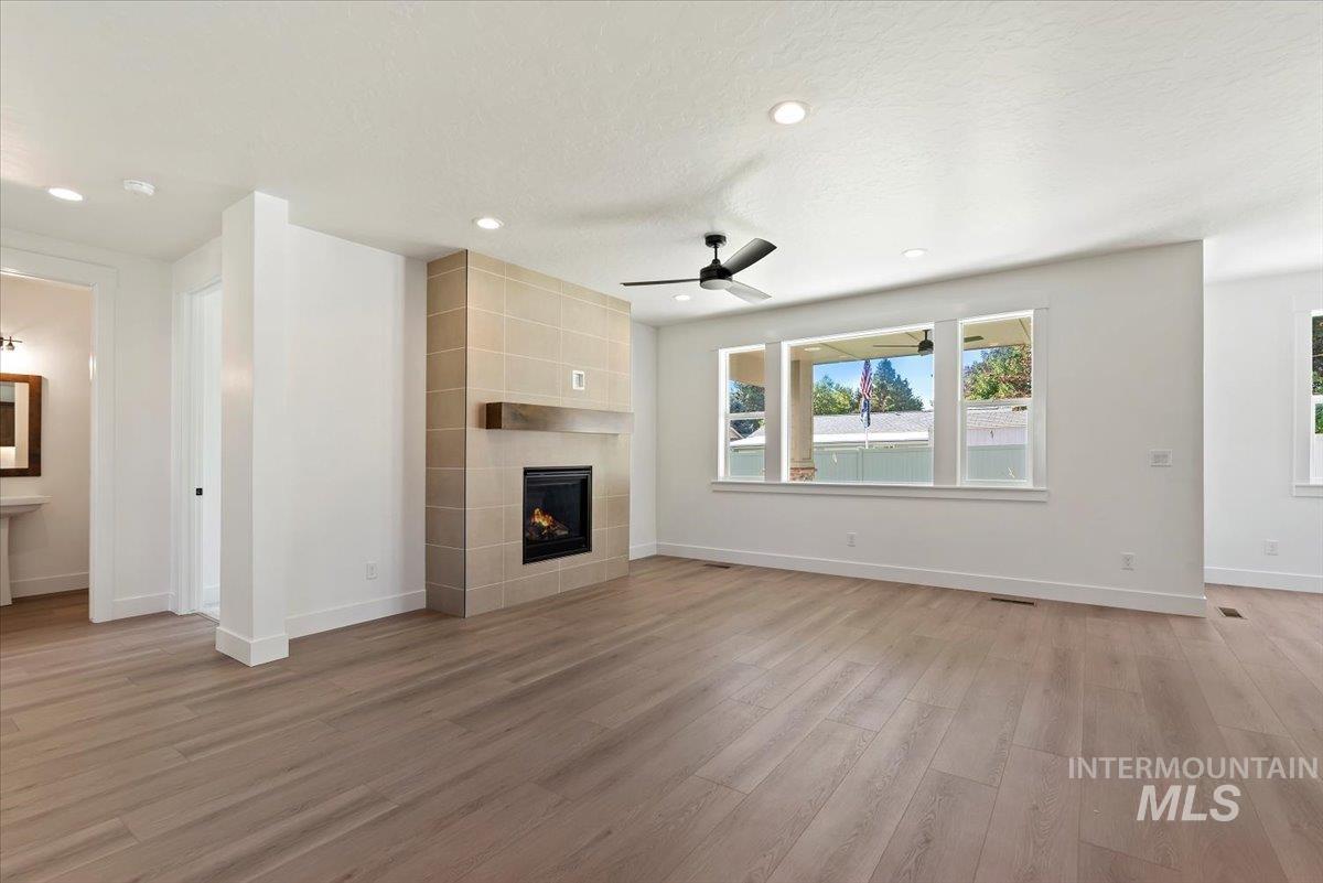 Unfurnished living room with a ceiling fan, recessed lighting, light wood finished floors, a fireplace, and a textured ceiling