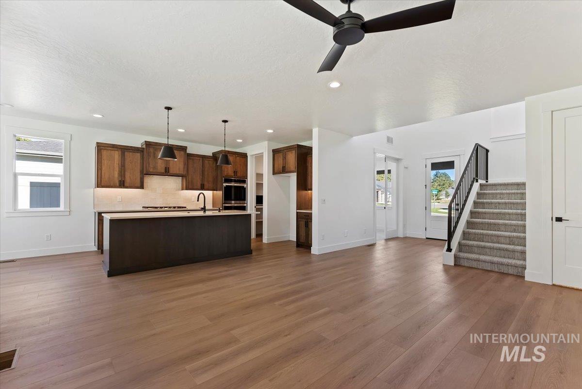 Unfurnished living room featuring stairway, dark wood-style flooring, ceiling fan, and recessed lighting