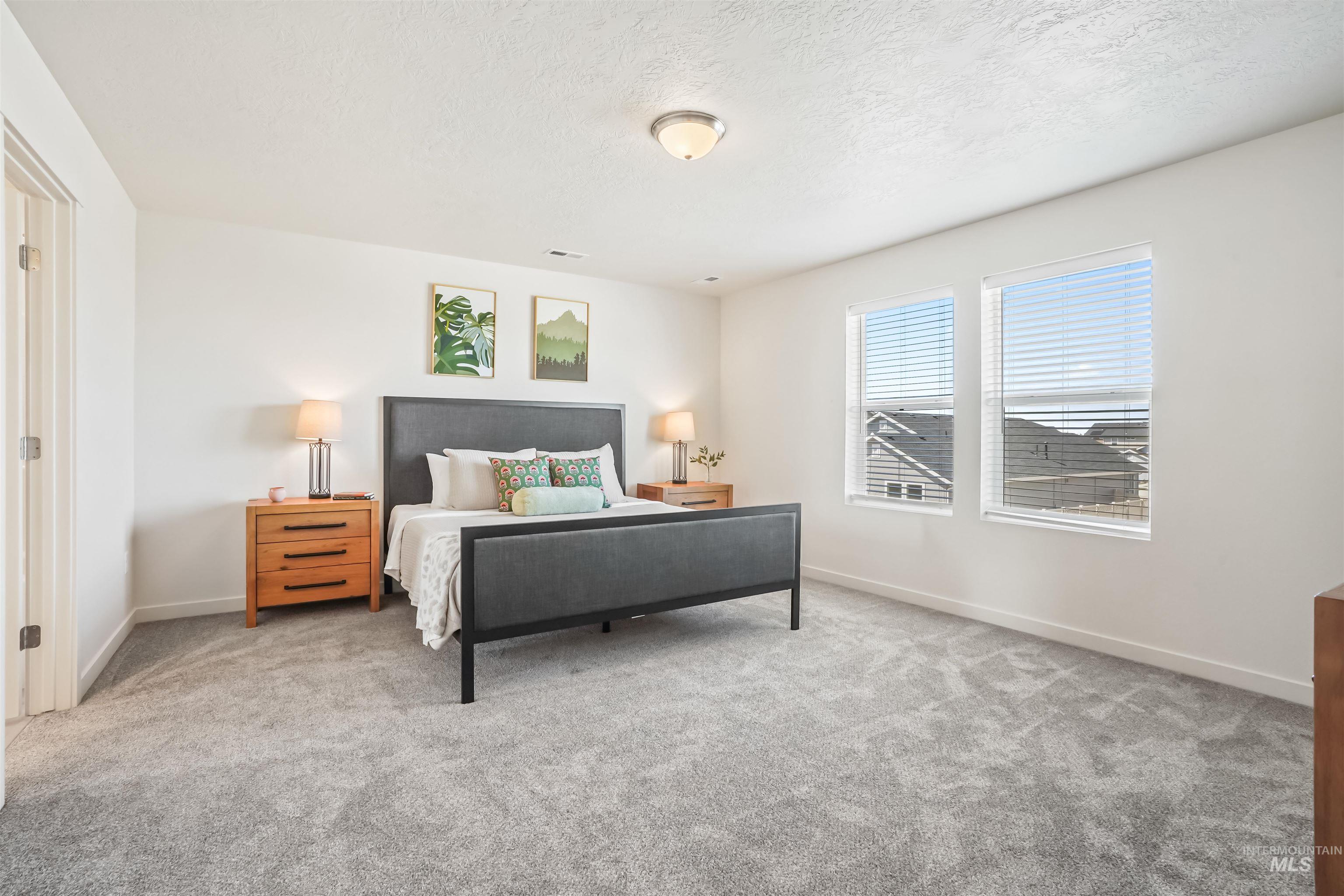 Carpeted bedroom with a textured ceiling and baseboards