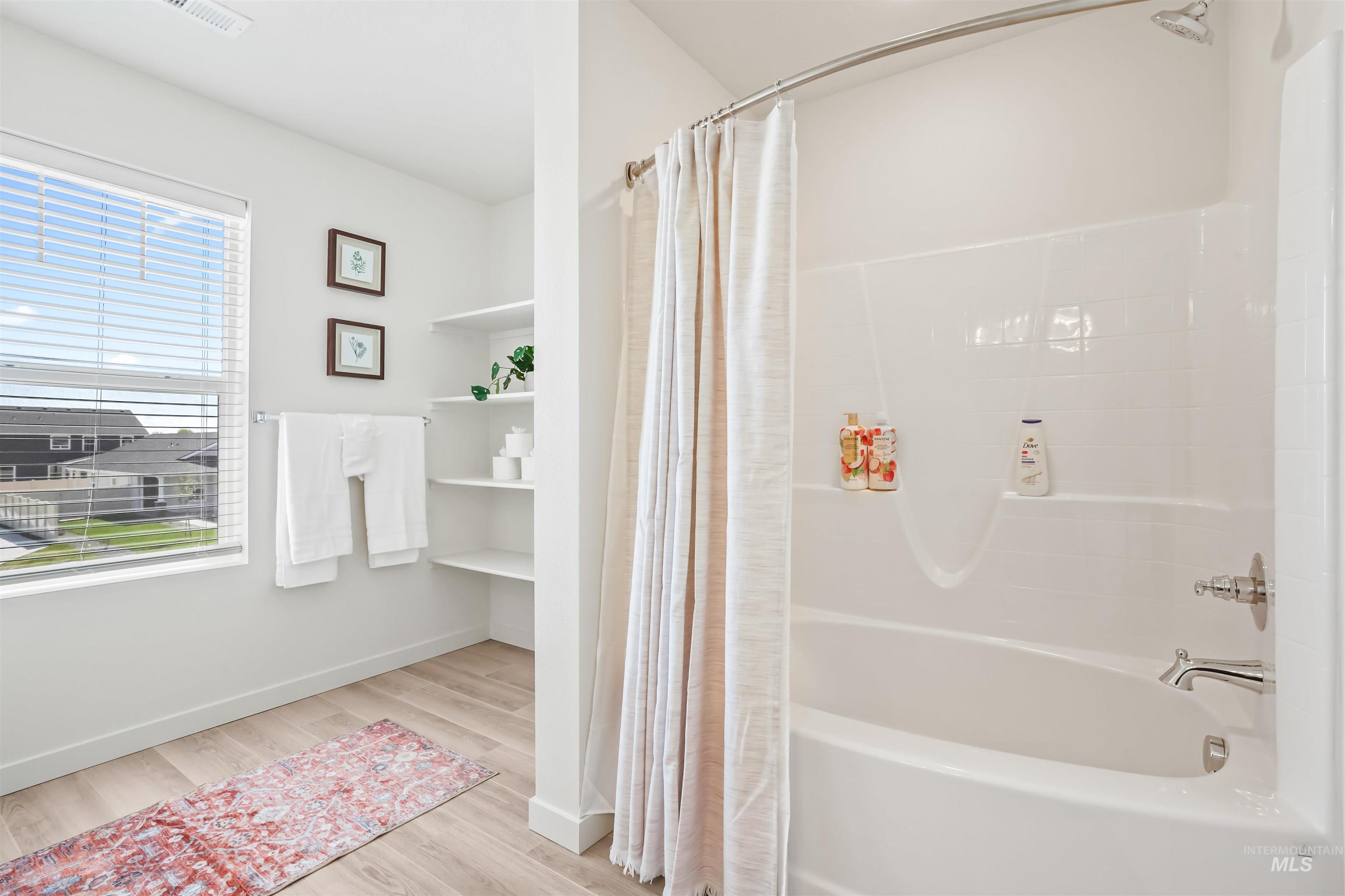 Full bath with light wood-type flooring and shower / bath combo