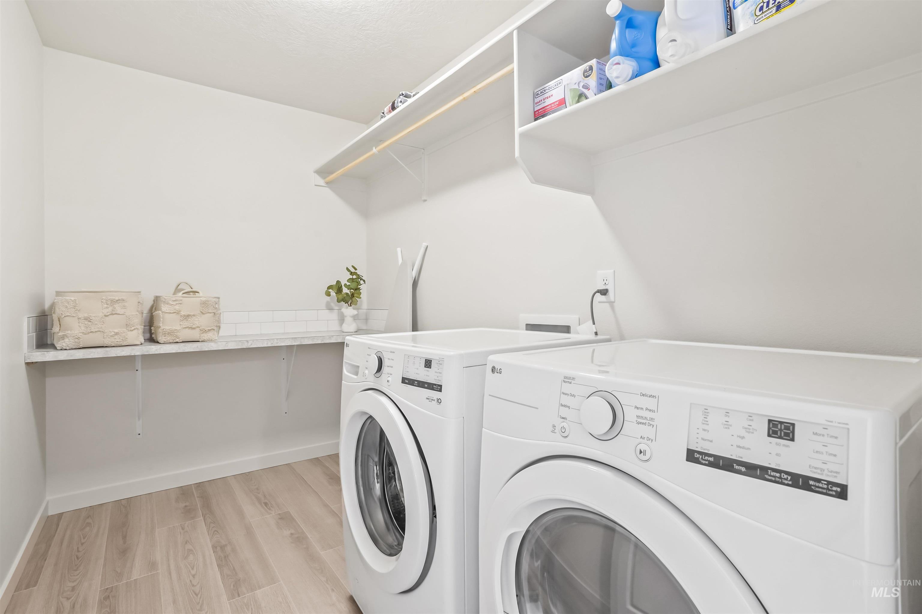 Laundry area with light wood-style flooring and washing machine and dryer