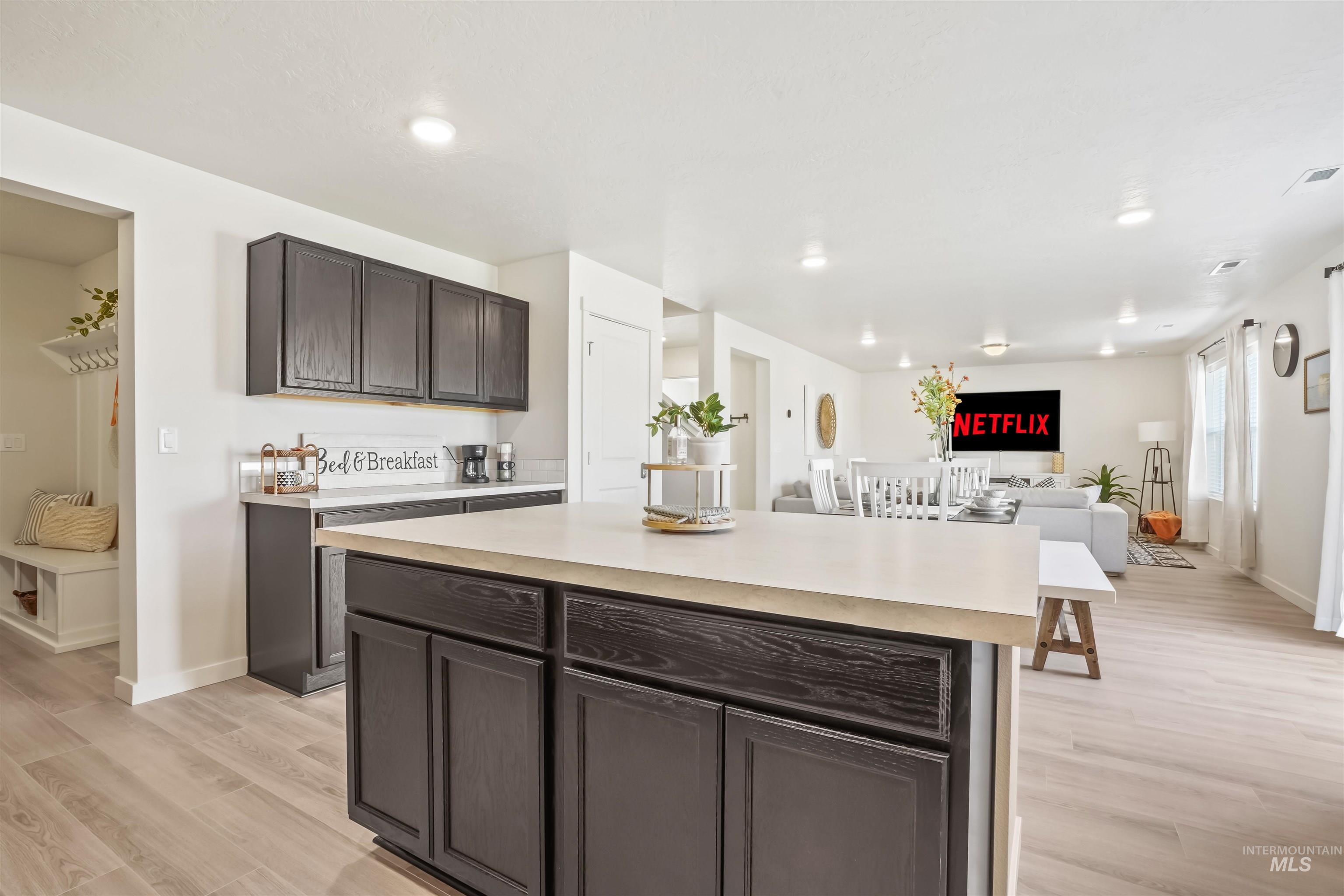 Kitchen with dark brown cabinetry, light wood-style floors, light countertops, a kitchen island, and recessed lighting
