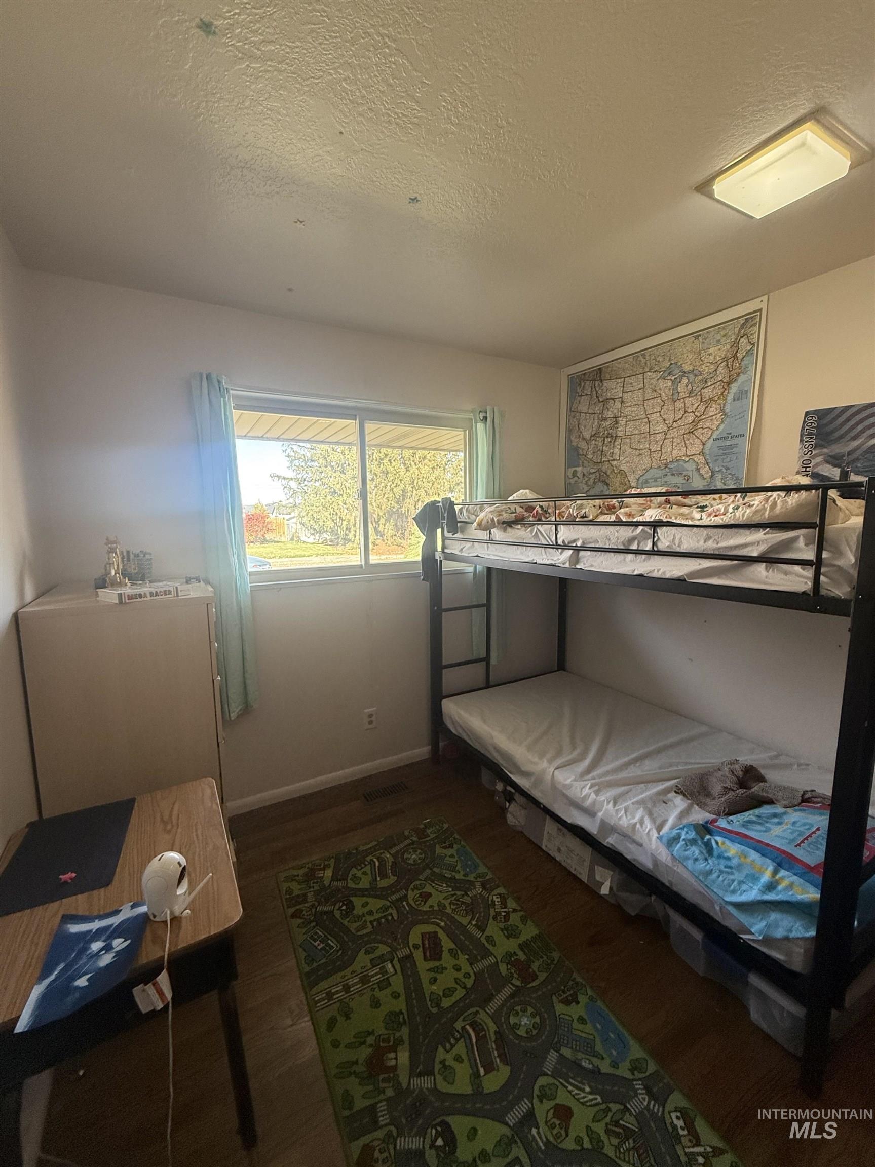Bedroom with dark wood-style floors and a textured ceiling