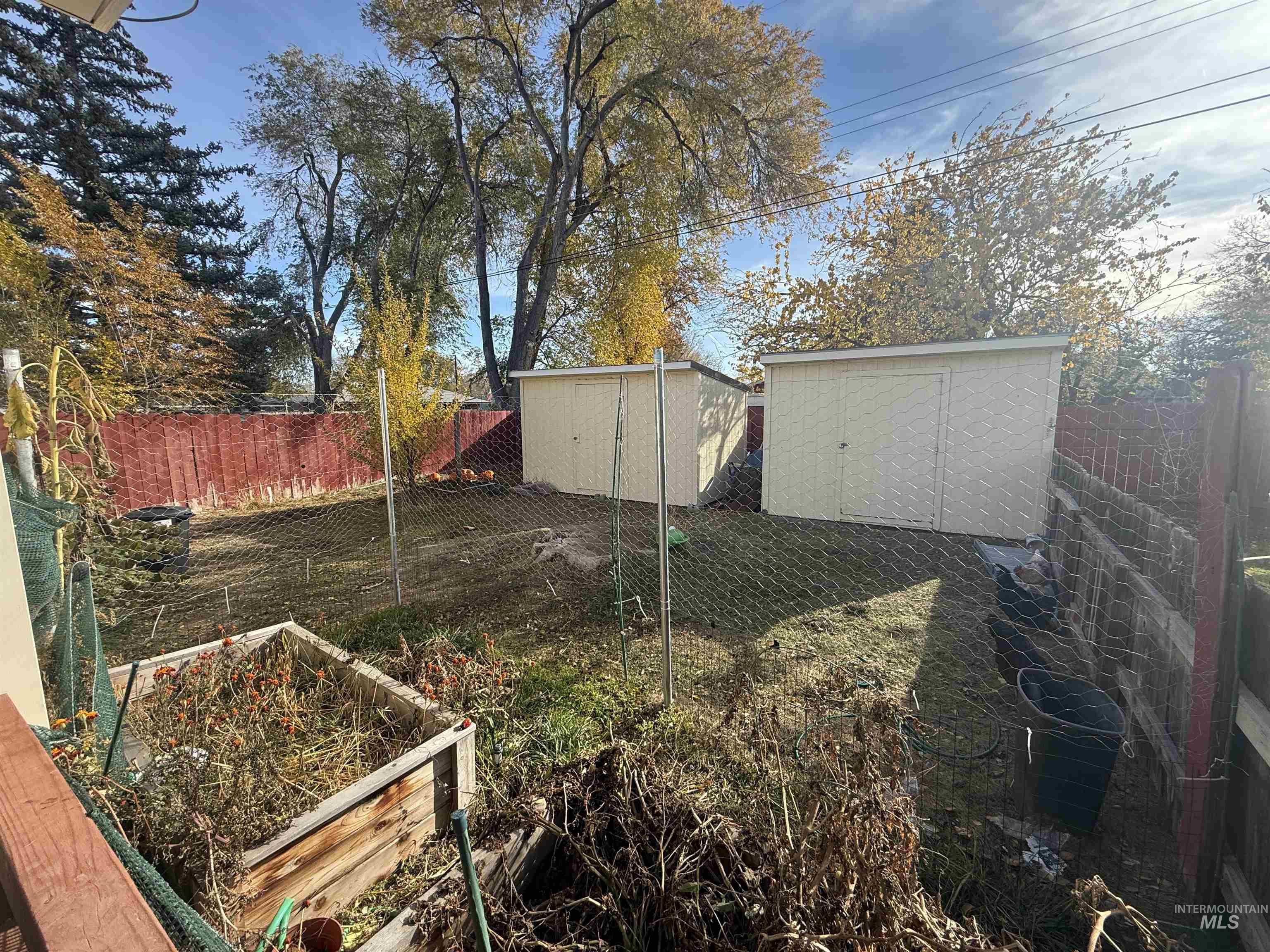 Fenced backyard featuring a storage shed and a garden
