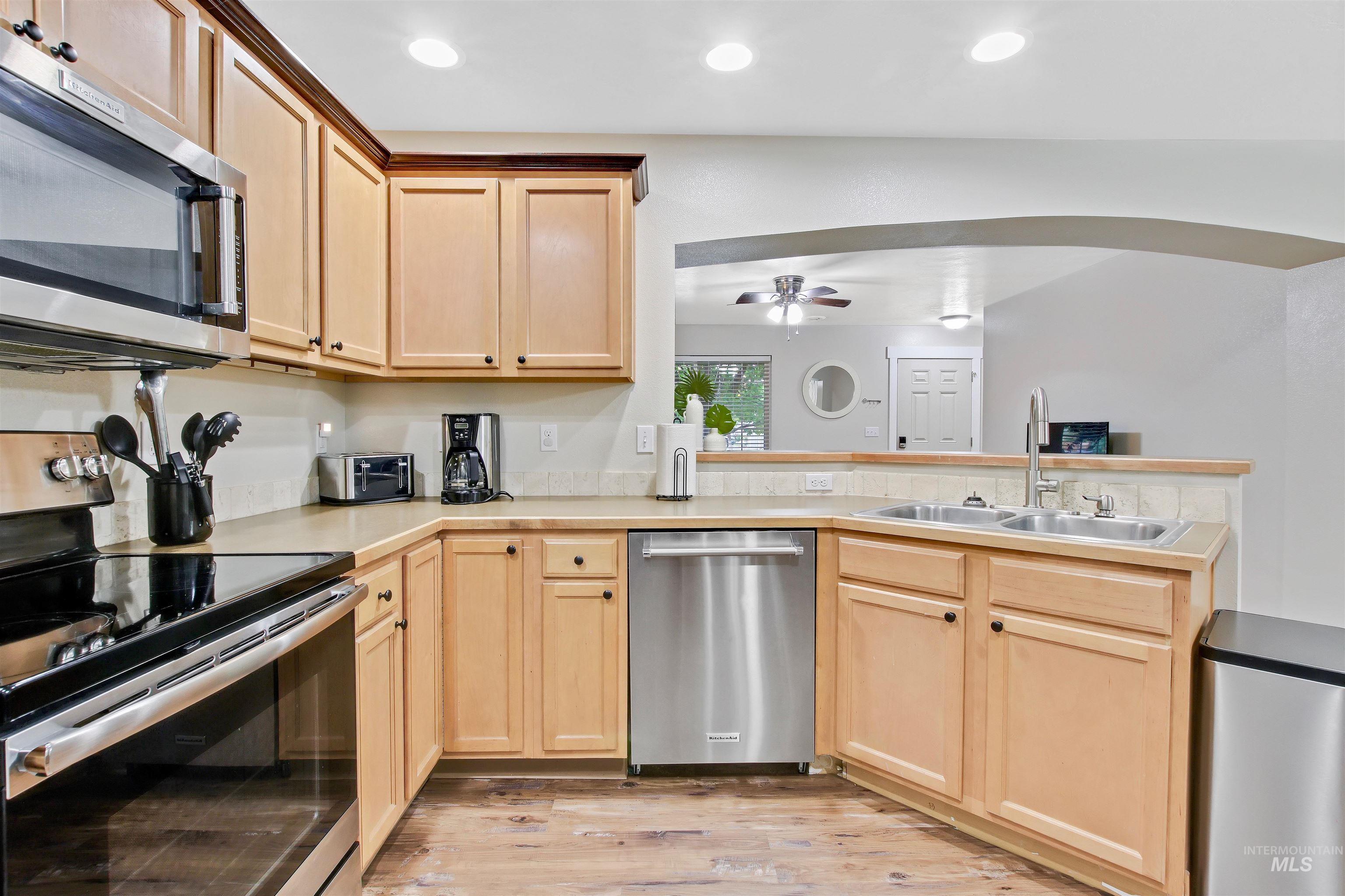 Kitchen featuring stainless steel appliances, light brown cabinetry, light countertops, light wood-type flooring, and recessed lighting
