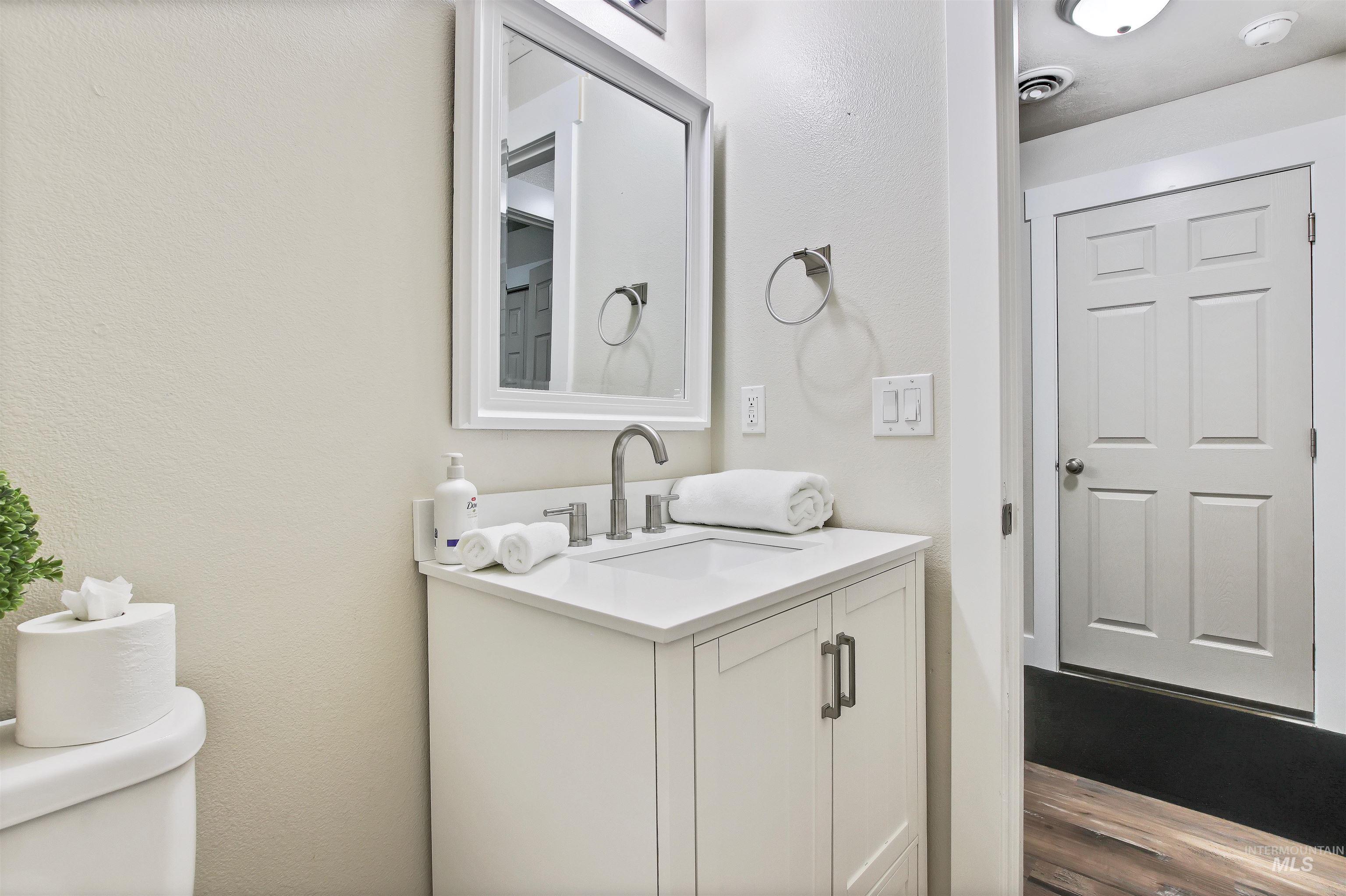 Bathroom featuring vanity, a textured wall, and dark wood-type flooring