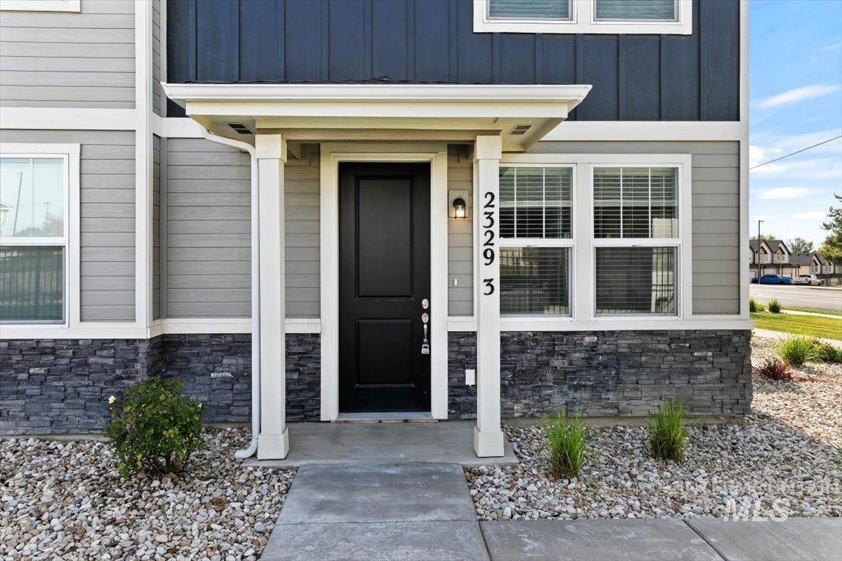 Doorway to property with stone siding and board and batten siding