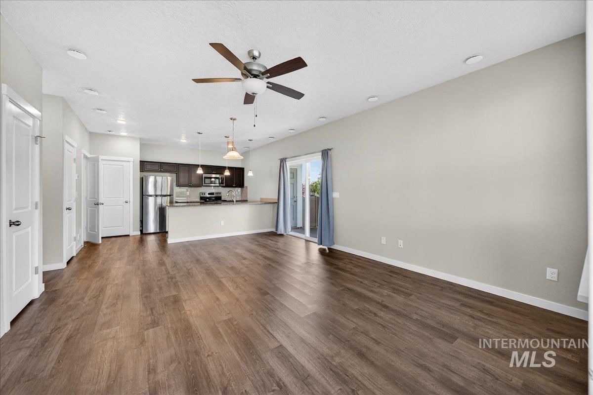 Unfurnished living room featuring dark wood finished floors, a textured ceiling, and ceiling fan