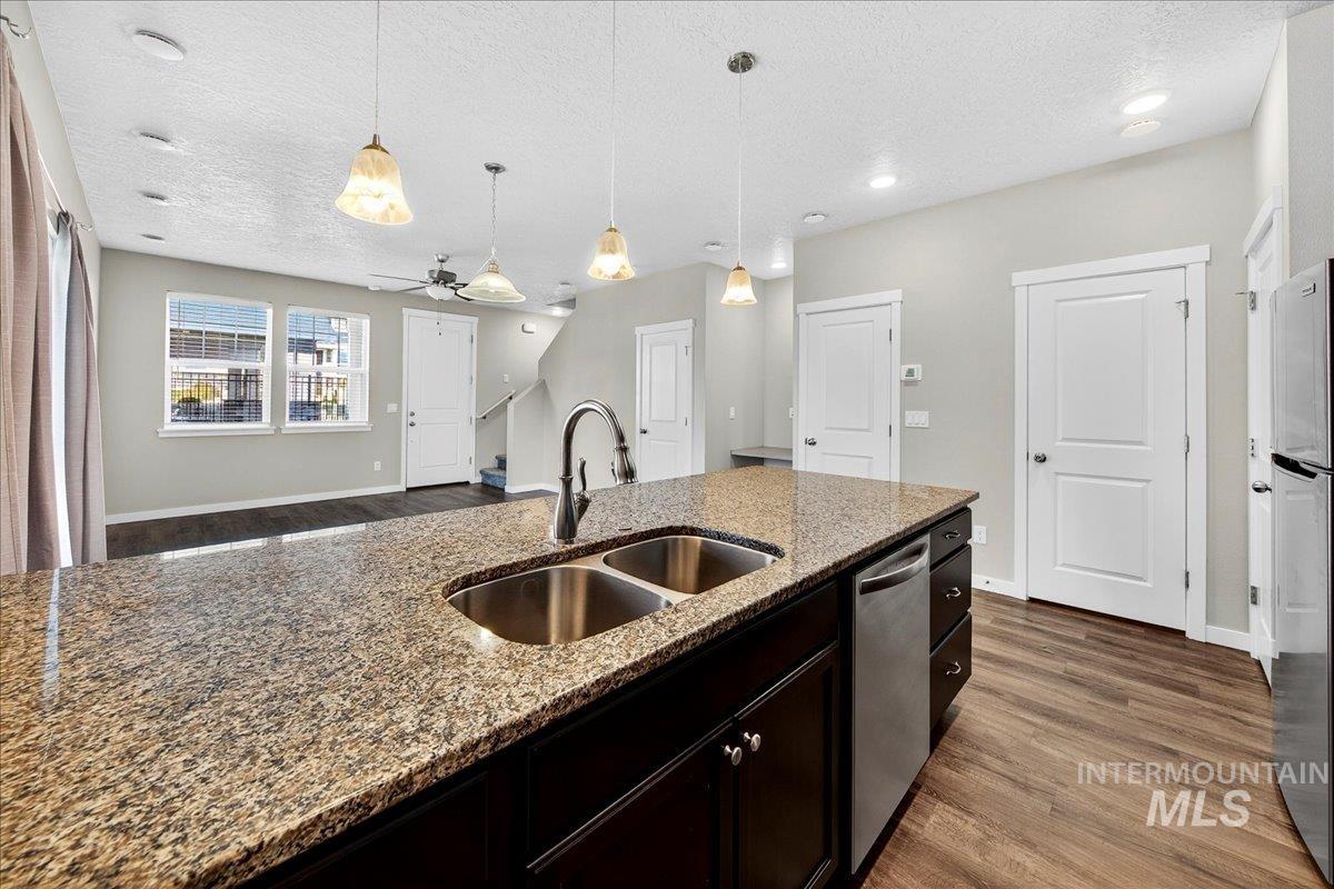 Kitchen with dark wood finished floors, open floor plan, pendant lighting, a textured ceiling, and stainless steel appliances