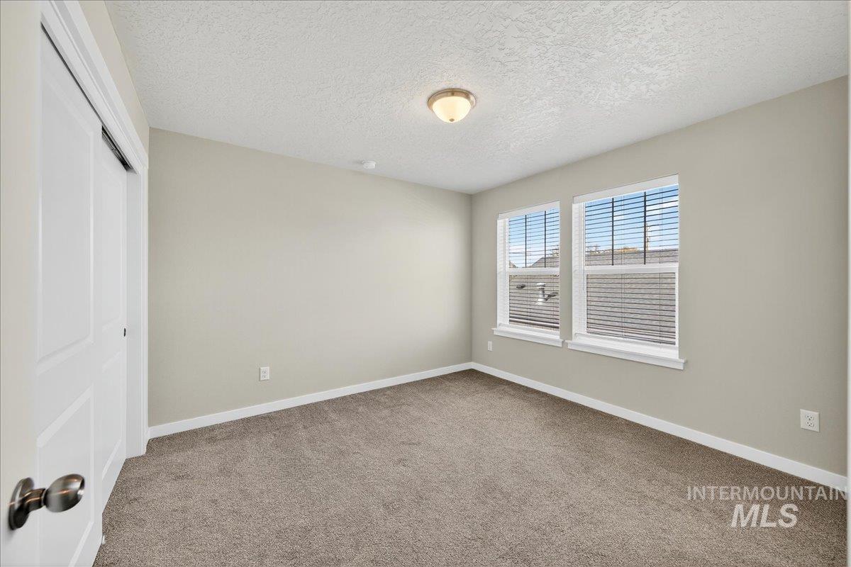 Unfurnished bedroom featuring light carpet, a closet, and a textured ceiling