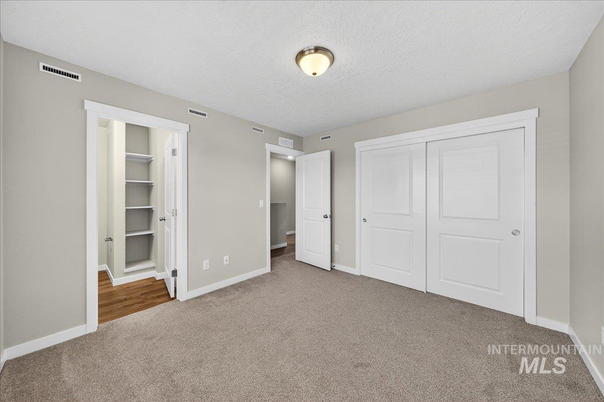 Unfurnished bedroom with a textured ceiling, a closet, and carpet floors