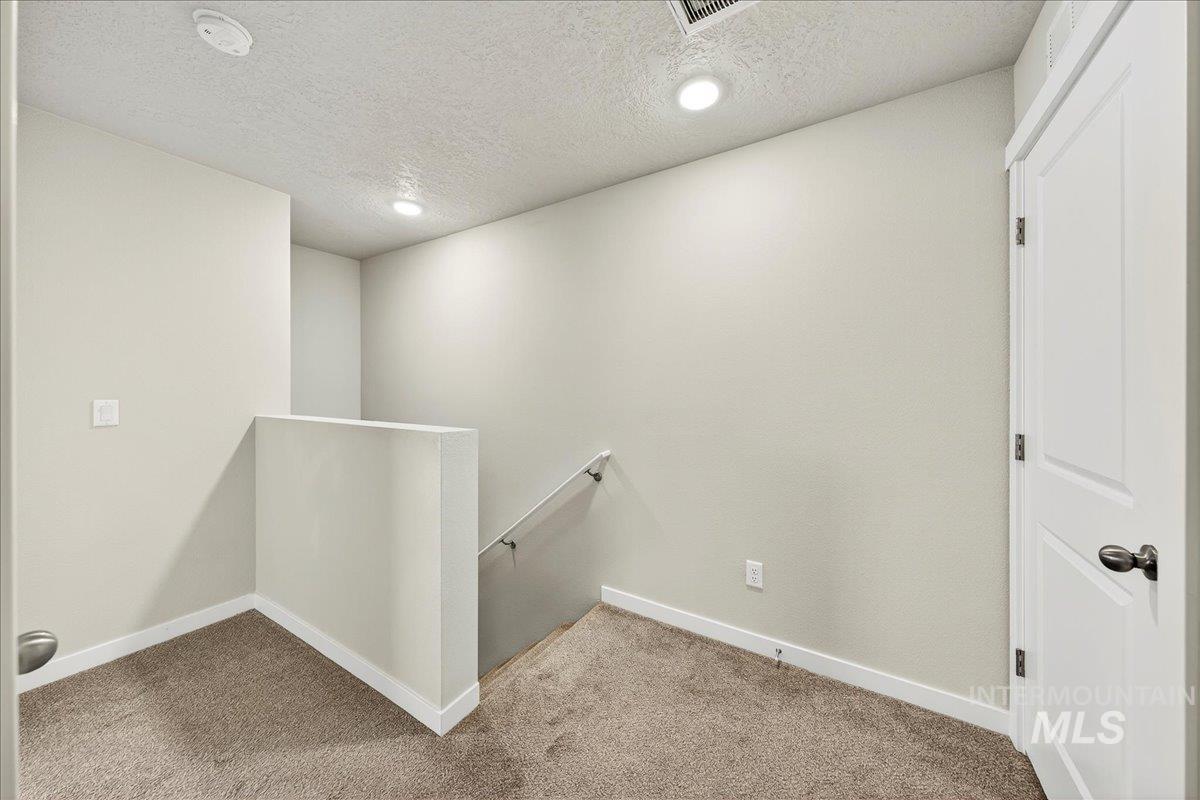 Hall with an upstairs landing, a textured ceiling, carpet floors, and recessed lighting