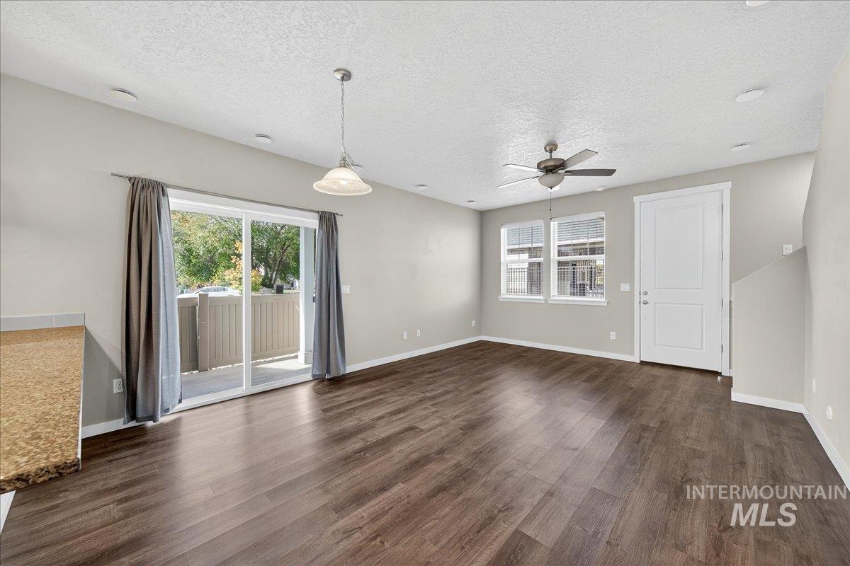 Unfurnished living room with dark wood finished floors, a textured ceiling, and a ceiling fan