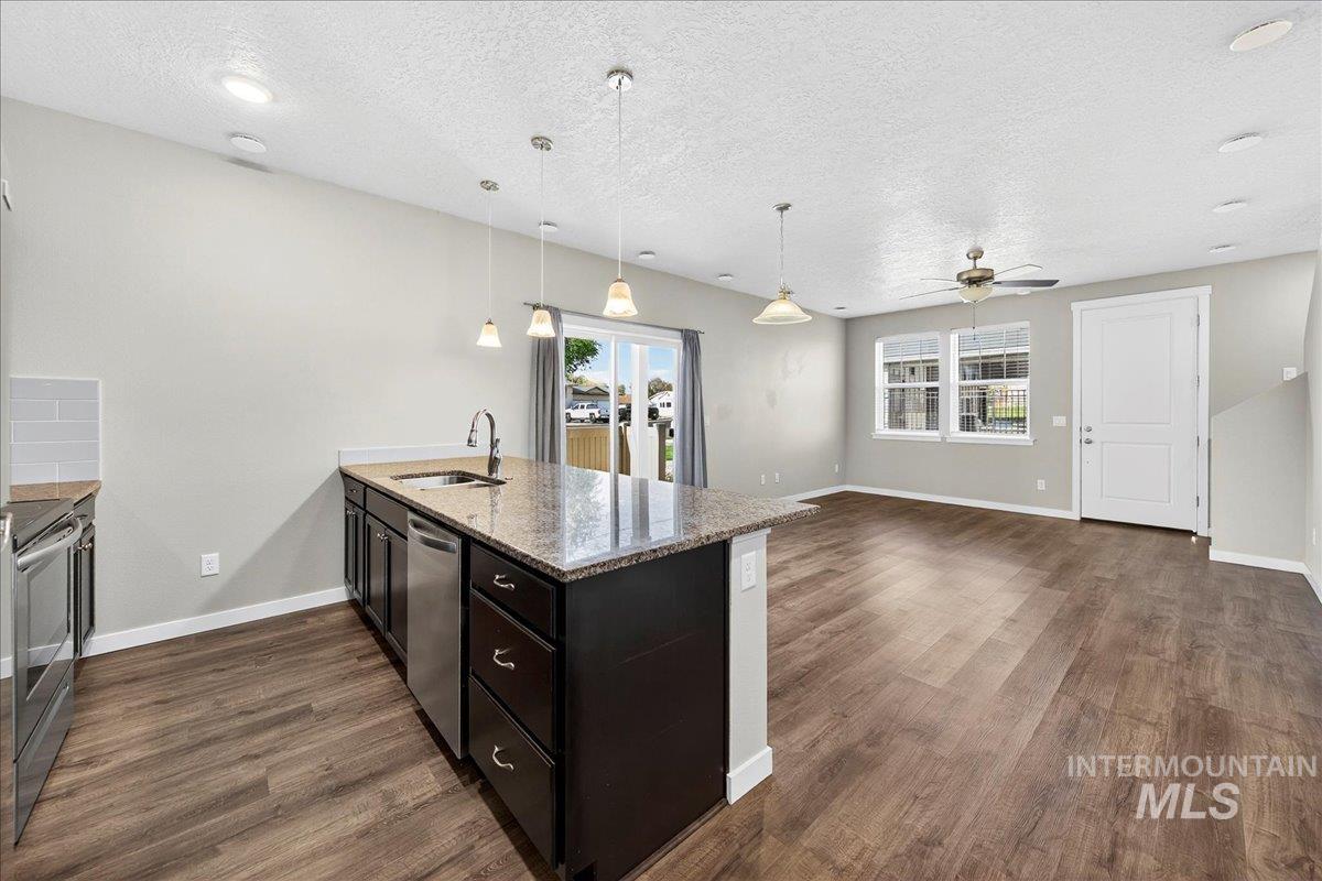 Kitchen with a peninsula, light stone countertops, plenty of natural light, hanging light fixtures, and a textured ceiling