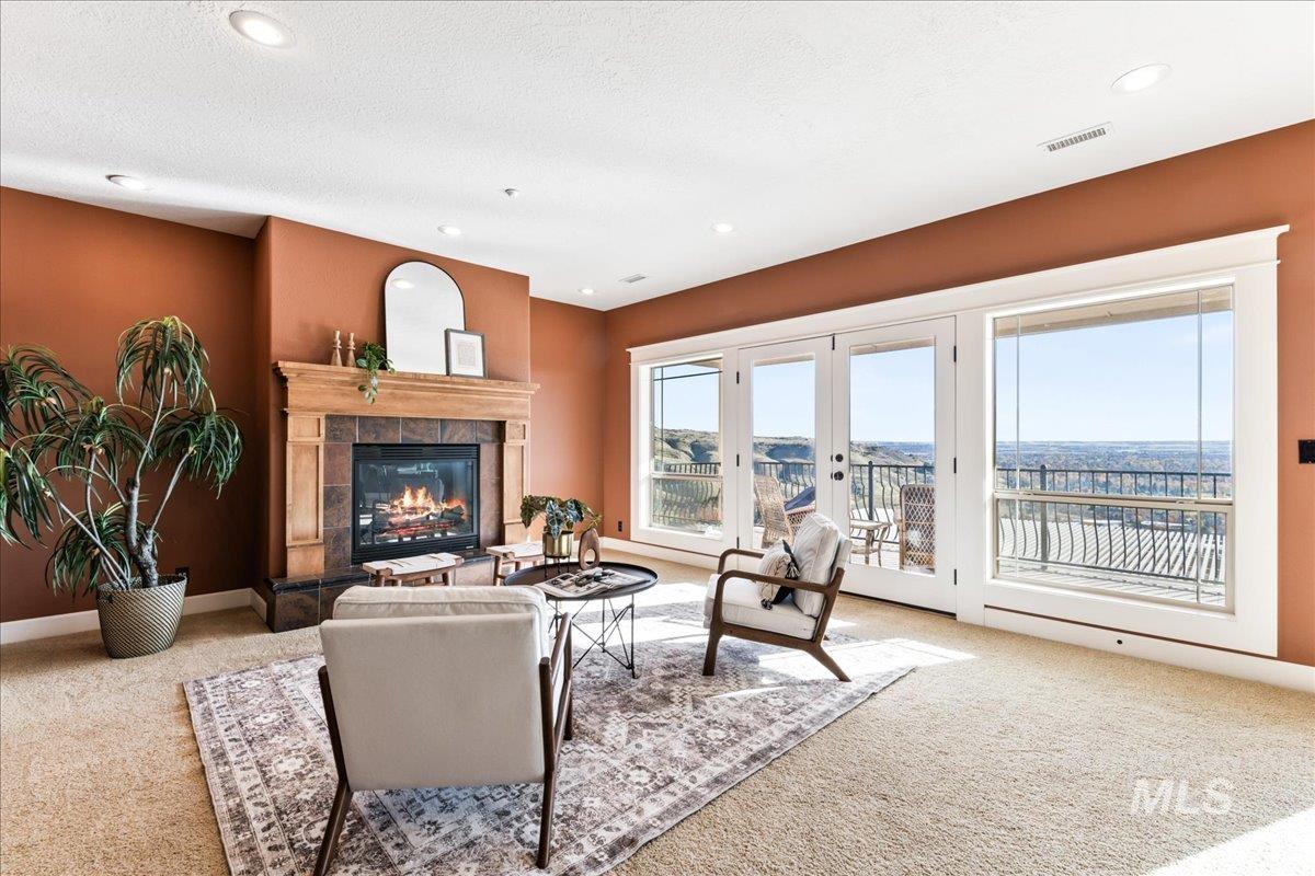 Living area featuring light colored carpet, a tiled fireplace, recessed lighting, and french doors