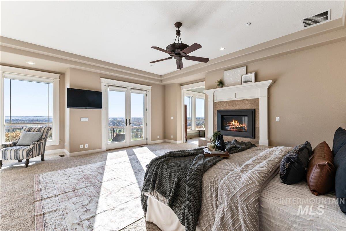 Bedroom with french doors, carpet, a tray ceiling, access to outside, and multiple windows