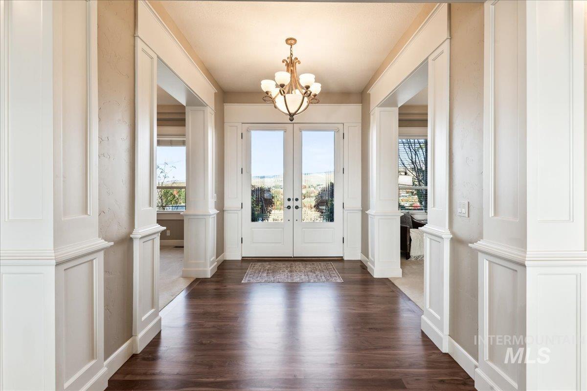 Foyer entrance featuring a decorative wall, french doors, dark wood-type flooring, decorative columns, and a wainscoted wall
