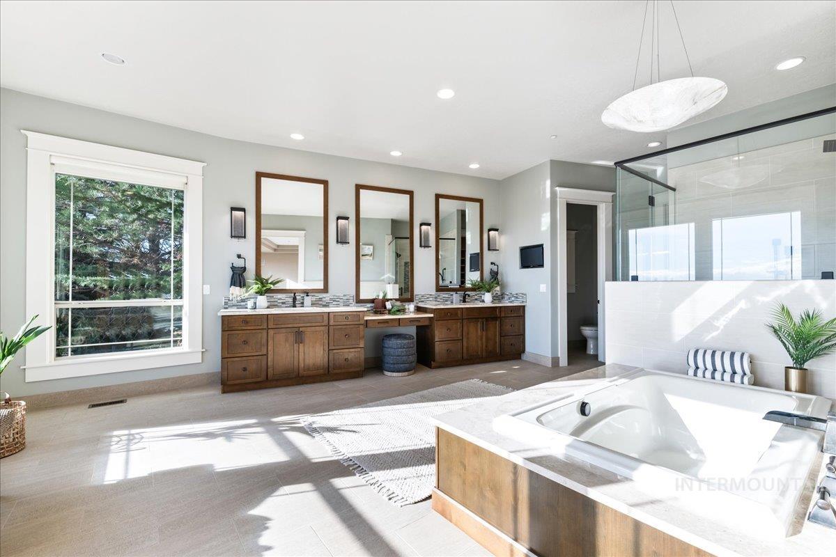 Full bath with plenty of natural light, two vanities, a bath, a shower stall, and recessed lighting
