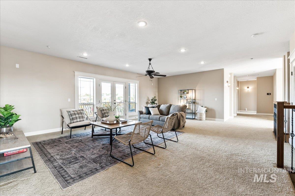 Carpeted living area featuring a textured ceiling, recessed lighting, a ceiling fan, and french doors