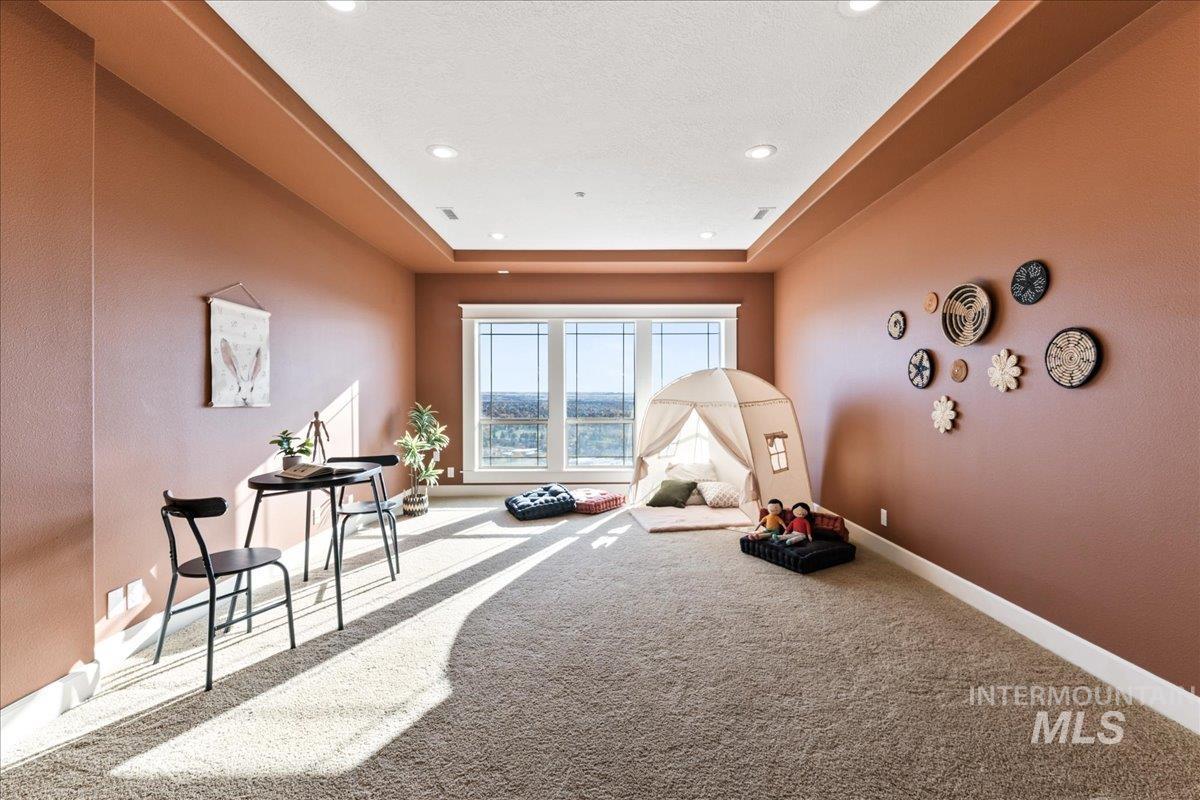 Playroom featuring a raised ceiling, carpet floors, a textured wall, and recessed lighting